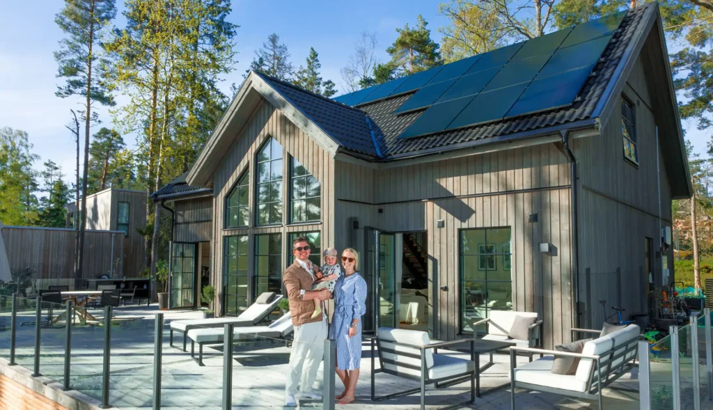 Familj framför en villa med installerade solceller